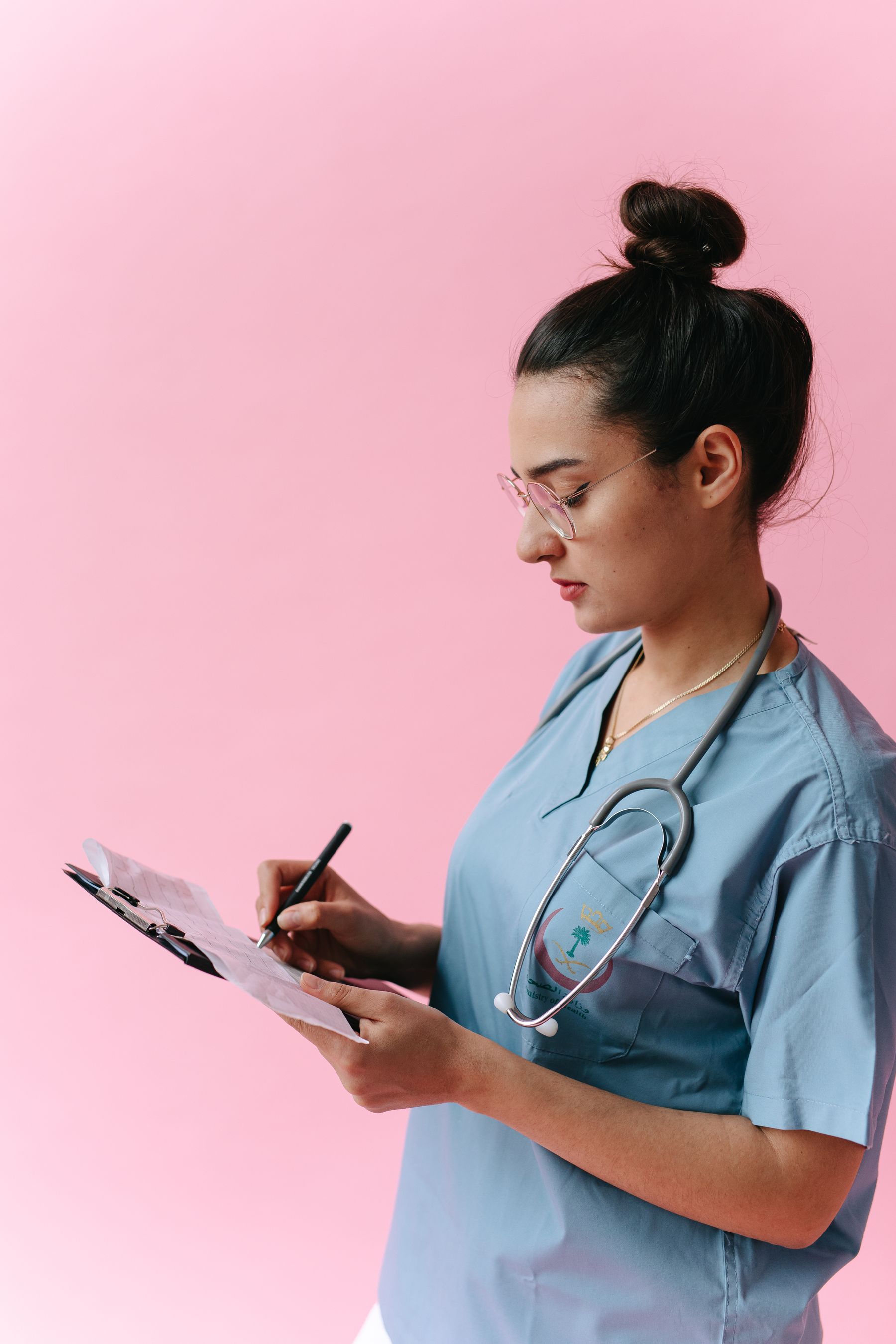 Healthcare professional in blue scrubs preparing notes